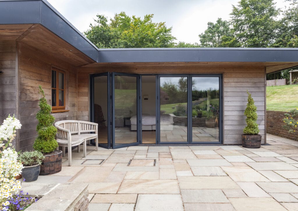 Visofold bifold doors in a grey colour, fitted to a new timber clad extension
