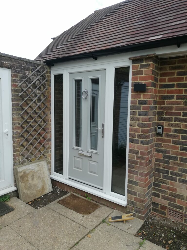 light grey new front door with side panels to a brick porch