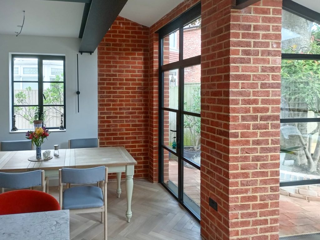 picture of steel look french doors in a dining area, brick extension.