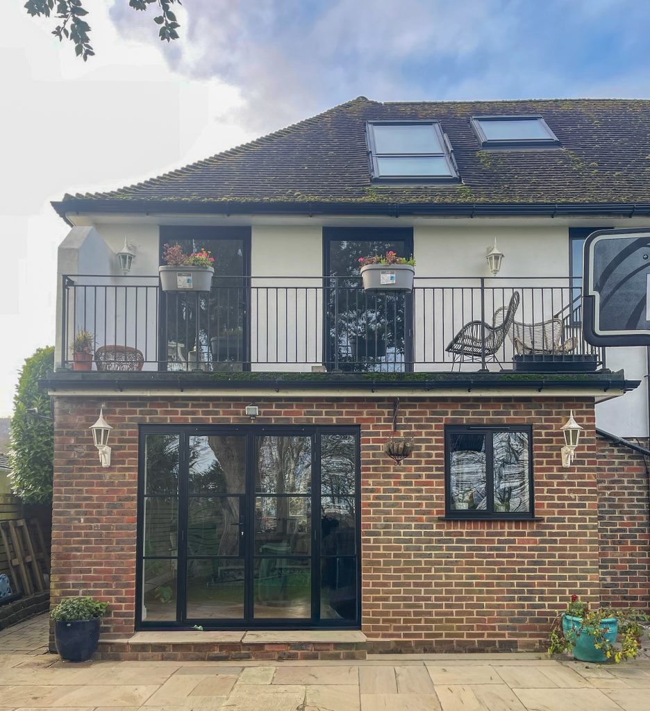 Slimline windows and doors showing balcony single doors on the first floor of a modern house with heritage doors and kitchen window to the side.