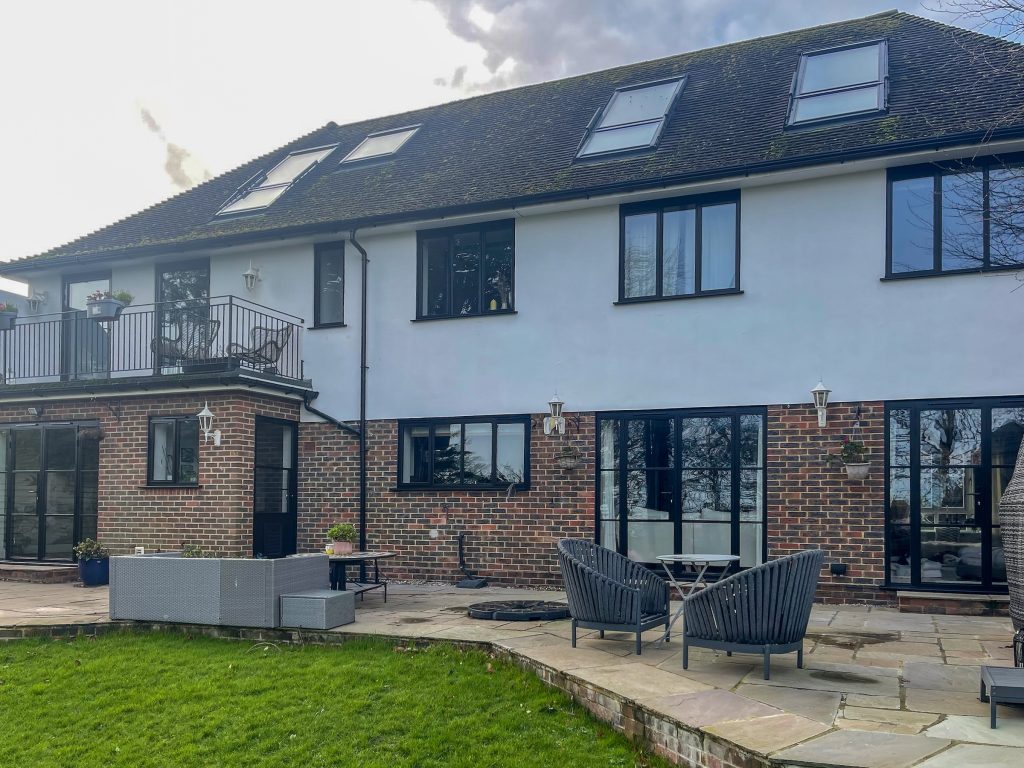 slimline windows to the back of a contemporary house with white render and classic brickwork